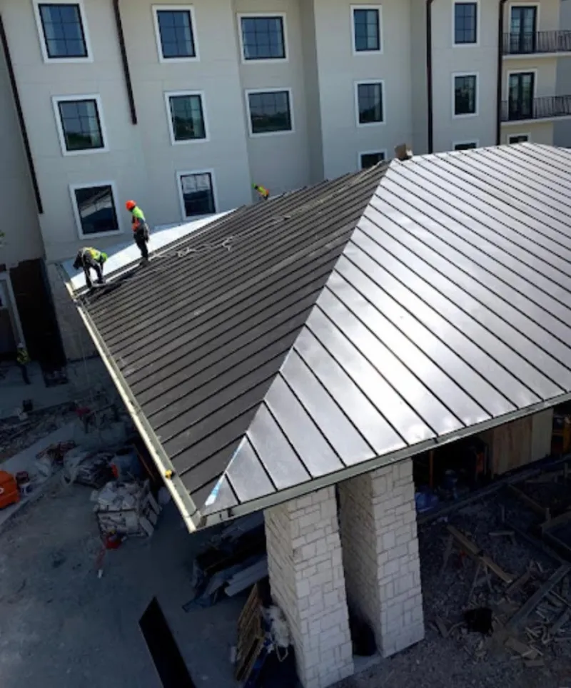 Crew installing standing seam metal roof panels on a commercial project in Coal